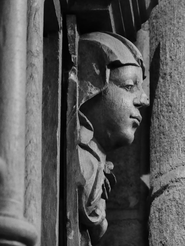 Visage sculpté en bois, vu de profil.